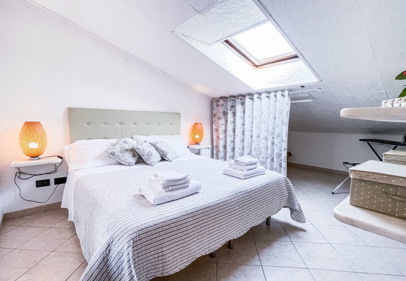 Camera da letto matrimoniale in mansarda: arredamento semplice, appendiabiti, comodini e ripiani per un'accogliente atmosfera di riposo Camera da letto matrimoniale con arredamento semplice in stile mansarda. Presenta appendiabiti, comodini e ripiani per abiti, creando un ambiente acco