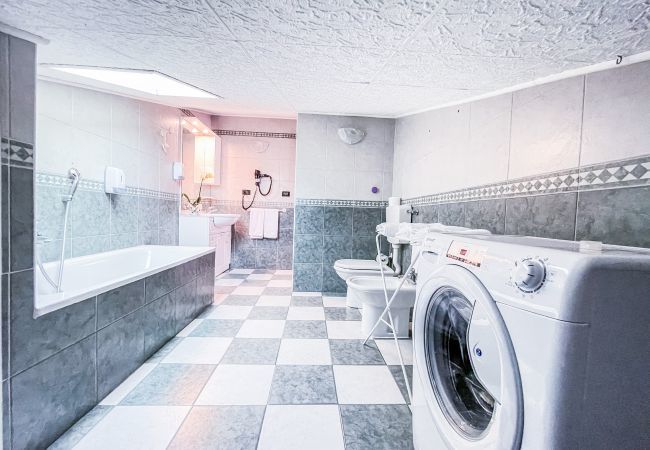 Bathroom MYHOUSE INN TORINO -Solo Affitti Brevi Overview of the bathroom with modern furnishings, illuminated mirror, bathtub/shower, towels, essential accessories and washing machine.