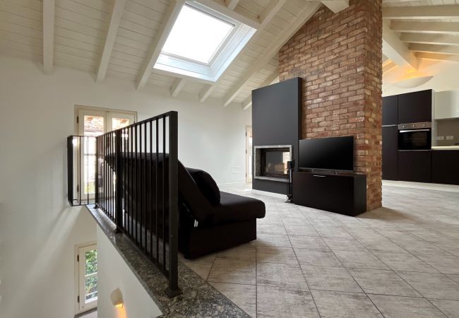 Open-plan living room with fireplace and skylight on raised level Bright open-plan living room with fireplace, TV, skylight, and central brick wall