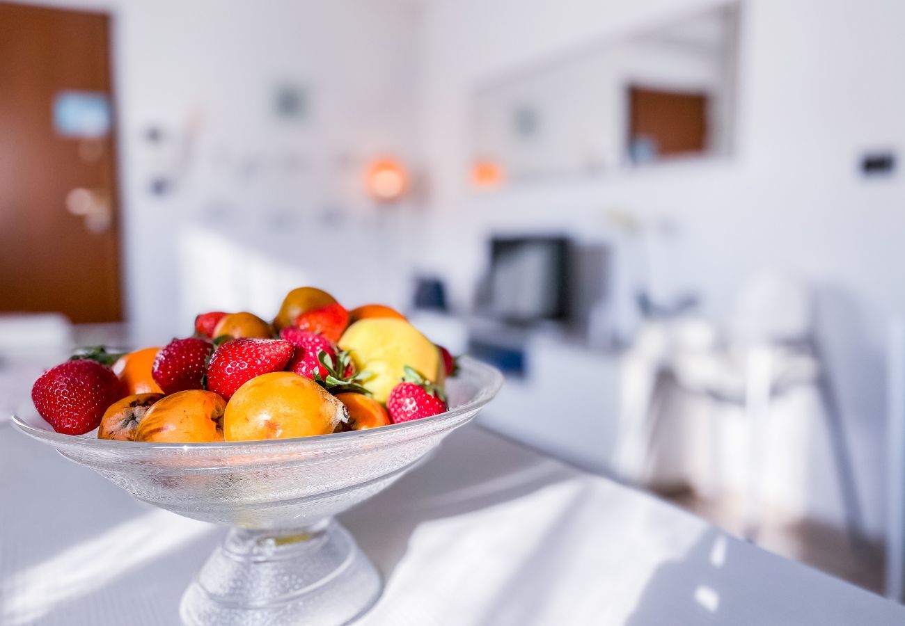 Living room detail MYHOUSE INN TORINO -Solo Affitti Brevi Dining table set up with a fruit centerpiece, creating a welcoming and inviting atmosphere.